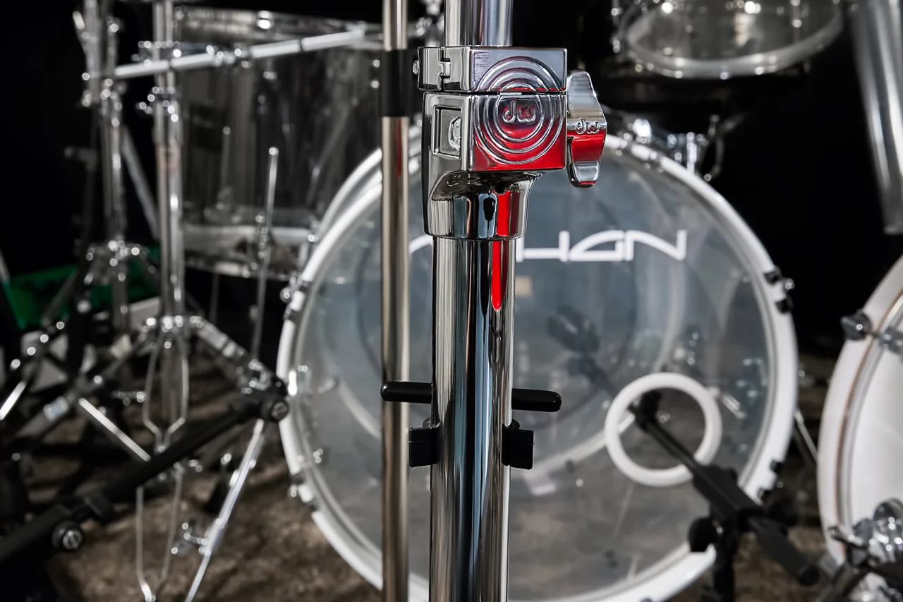Verchromte Tom-Halterung mit rotem Logo vor einer transparenten Acryl-Bassdrum